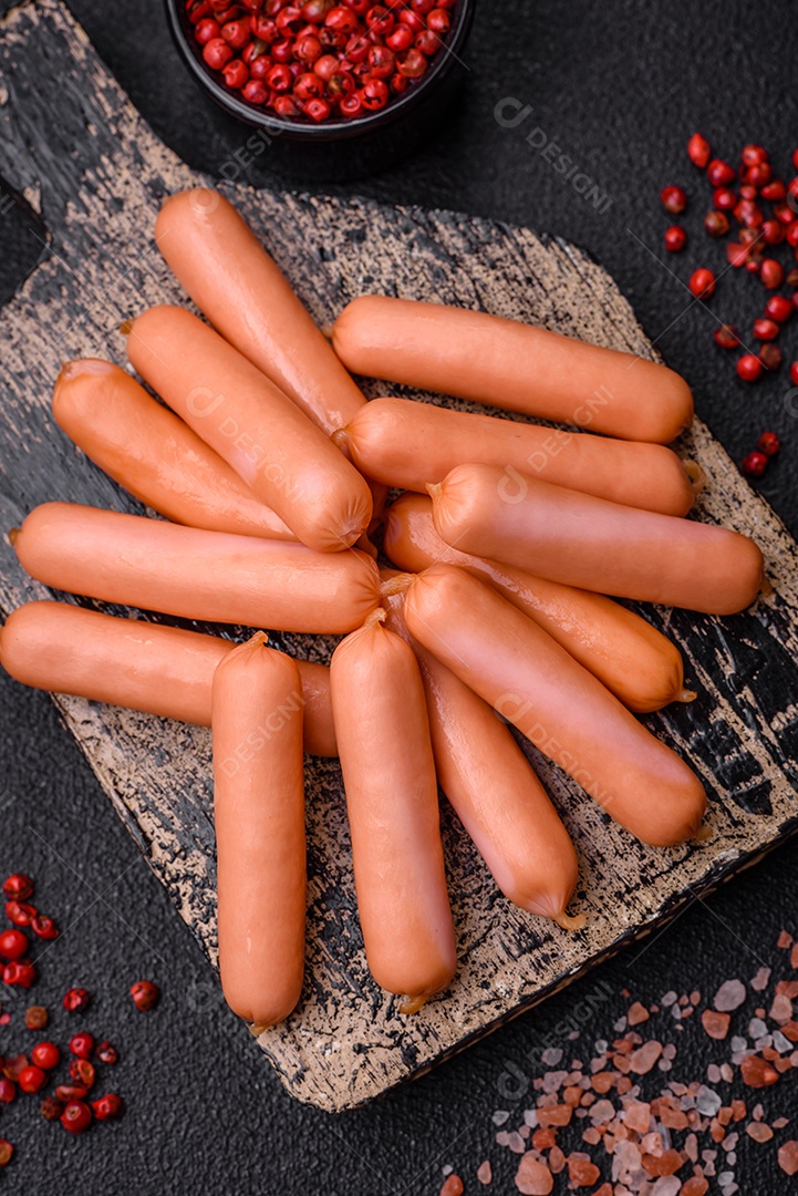 Deliciosas salsichas pequenas com sal, especiarias e ervas sobre um fundo escuro de concreto