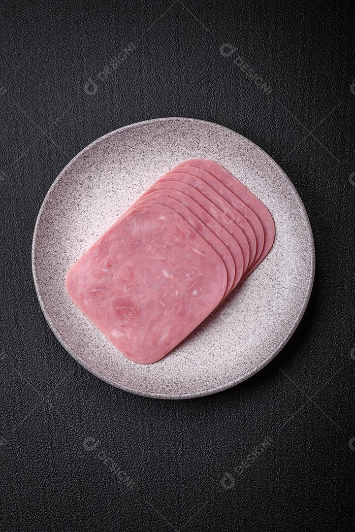 Delicioso presunto fresco cortado em fatias com sal, especiarias e ervas sobre um fundo escuro de concreto