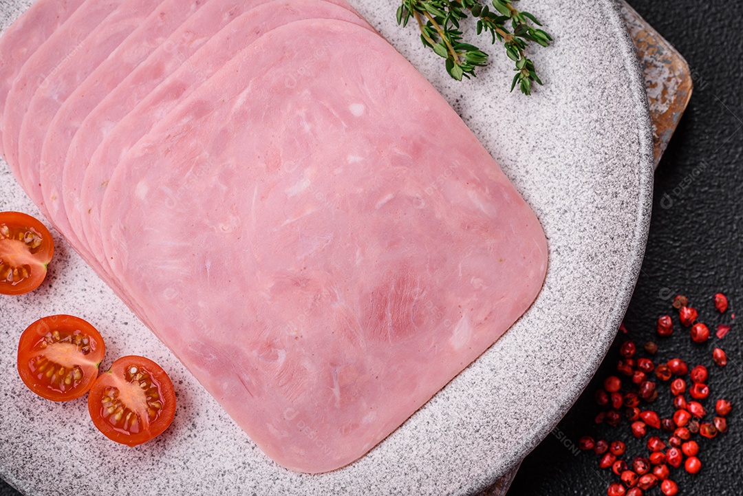 Delicioso presunto fresco cortado em fatias com sal, especiarias e ervas sobre um fundo escuro de concreto