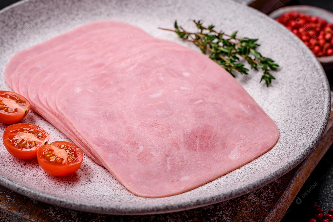 Delicioso presunto fresco cortado em fatias com sal, especiarias e ervas sobre um fundo escuro de concreto