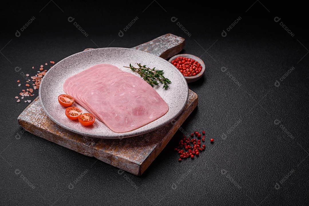 Delicioso presunto fresco cortado em fatias com sal, especiarias e ervas sobre um fundo escuro de concreto