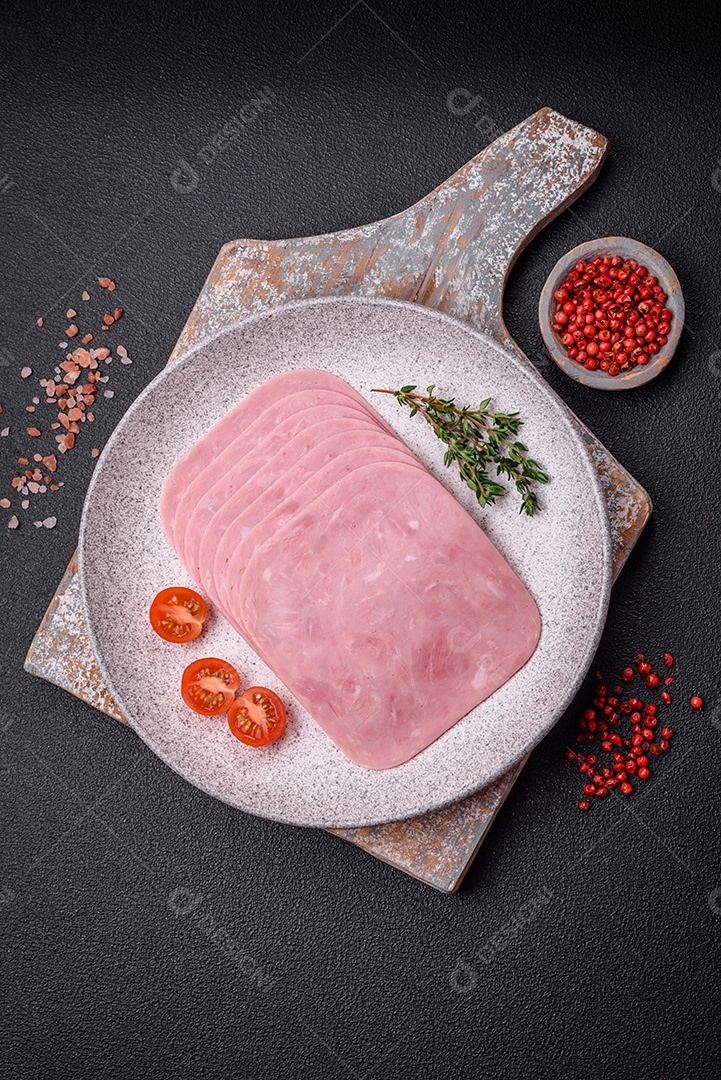 Delicioso presunto fresco cortado em fatias com sal, especiarias e ervas sobre um fundo escuro de concreto