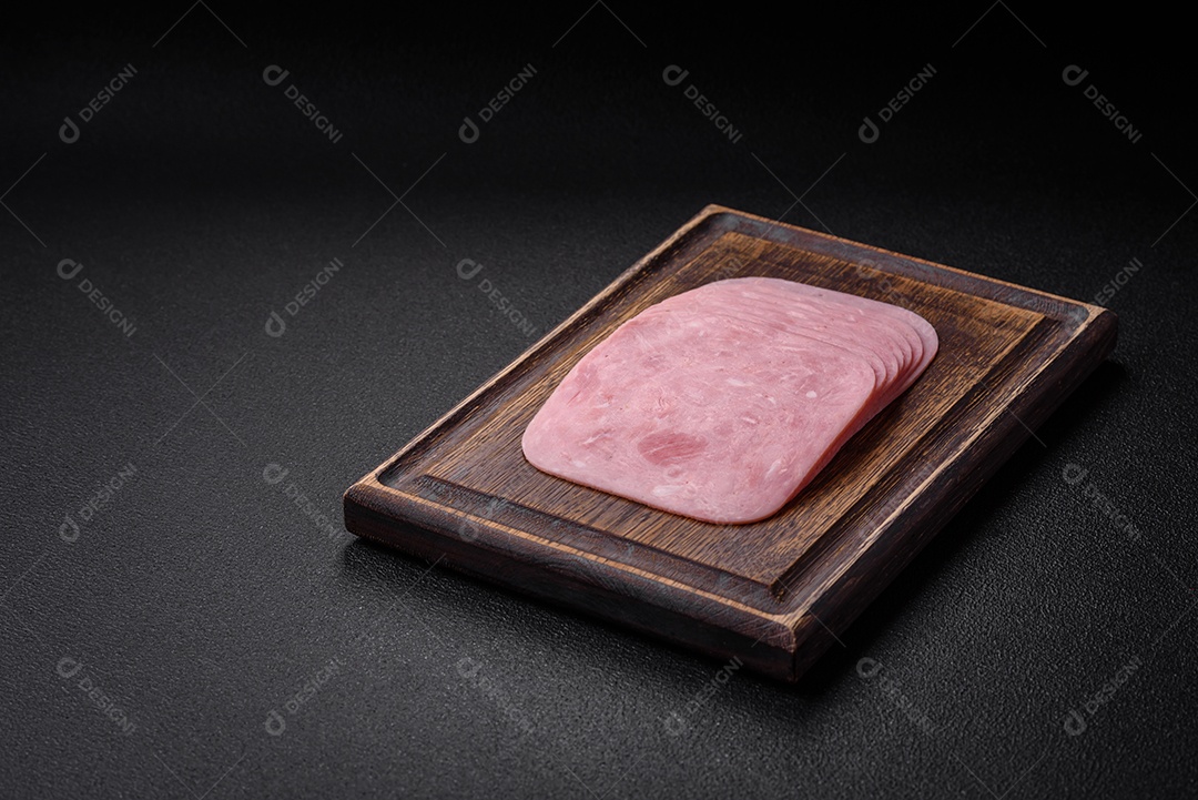 Delicioso presunto fresco cortado em fatias com sal, especiarias e ervas sobre um fundo escuro de concreto