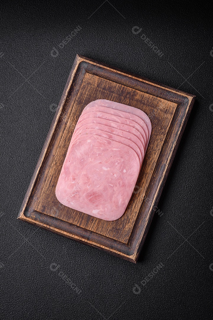 Delicioso presunto fresco cortado em fatias com sal, especiarias e ervas sobre um fundo escuro de concreto