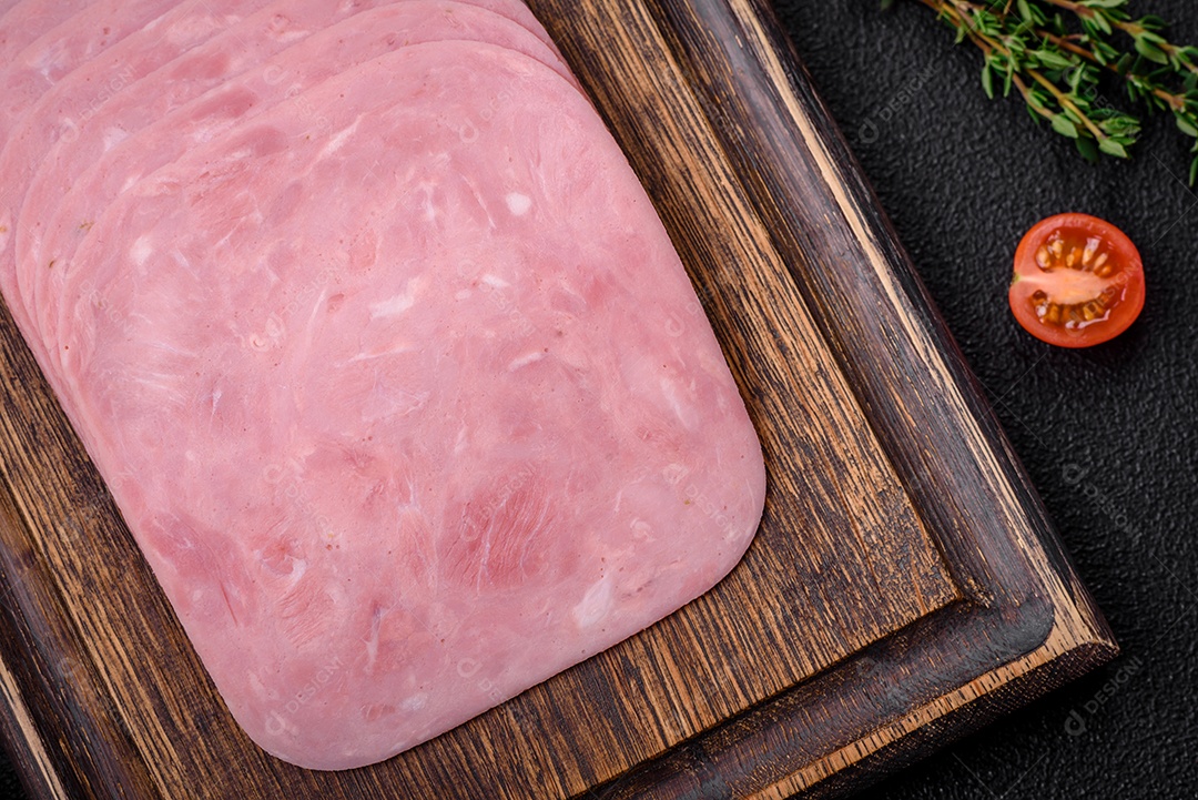 Delicioso presunto fresco cortado em fatias com sal, especiarias e ervas sobre um fundo escuro de concreto