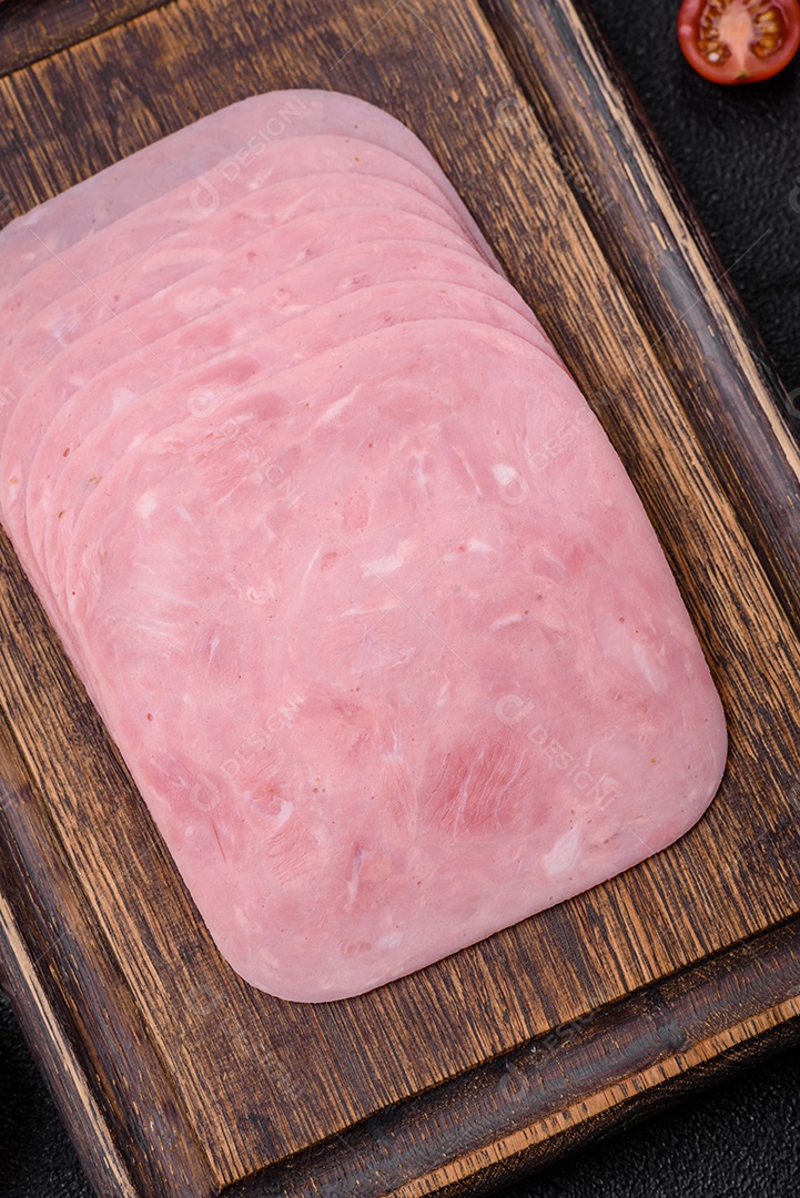 Delicioso presunto fresco cortado em fatias com sal, especiarias e ervas sobre um fundo escuro de concreto