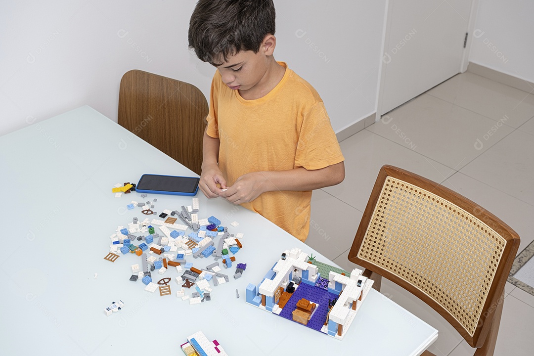 Criança brasileira de 10 anos de pijama brincando com blocos de construção.