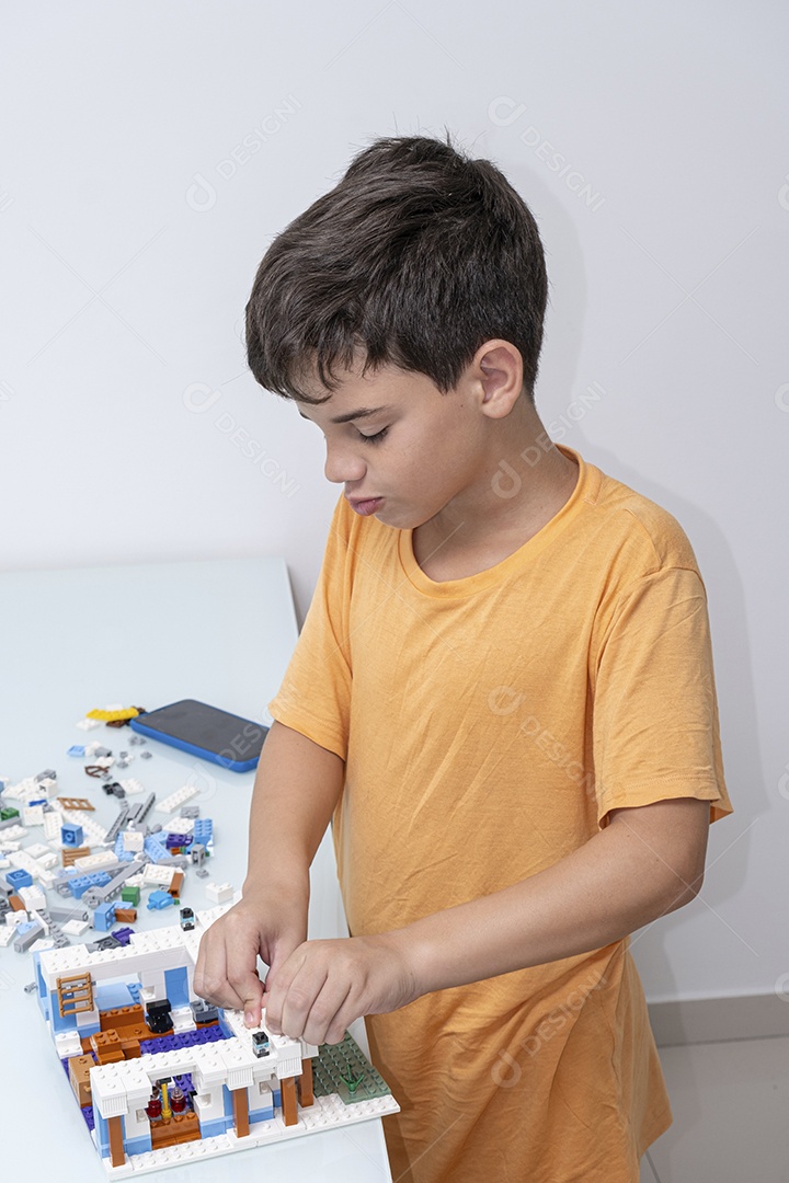 Criança brasileira de 10 anos de pijama brincando com blocos de construção.