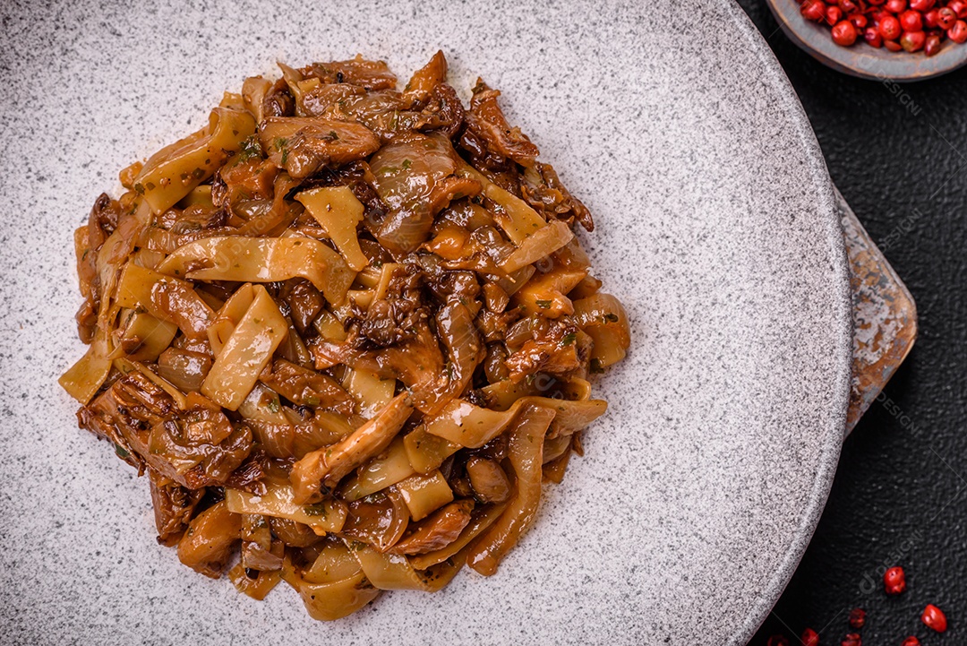 Delicioso prato de udon asiático com legumes, cogumelos, sal e especiarias numa placa cerâmica sobre um fundo escuro de concreto