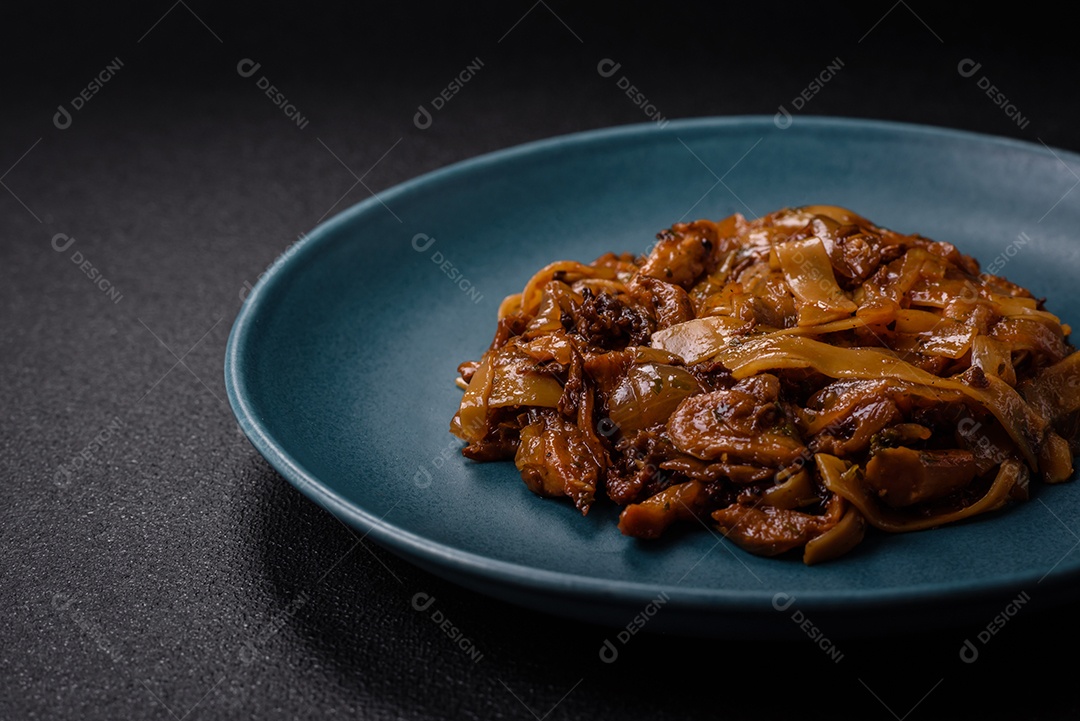 Delicioso prato de udon asiático com legumes, cogumelos, sal e especiarias numa placa cerâmica sobre um fundo escuro de concreto