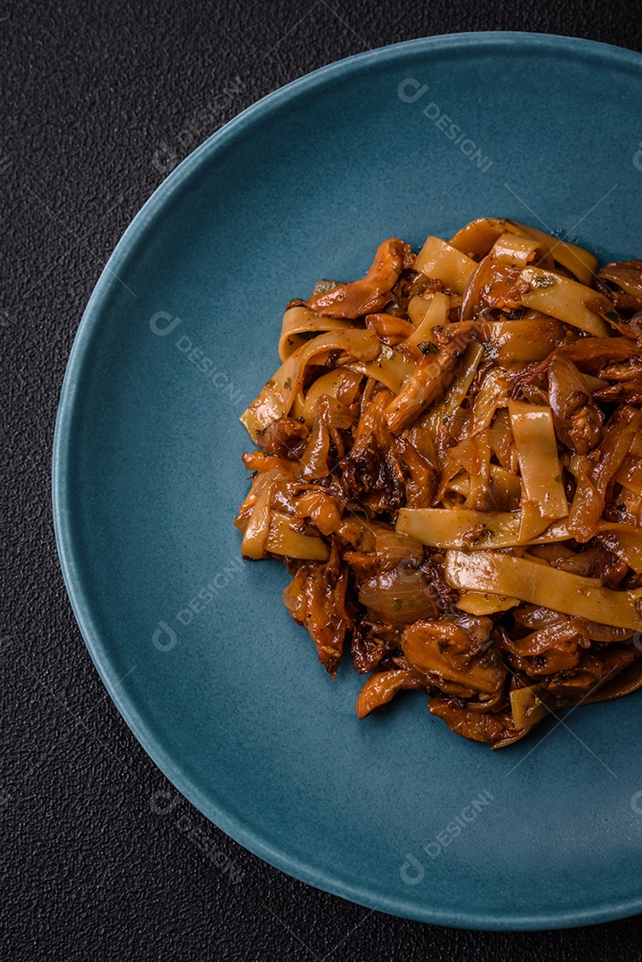 Delicioso prato de udon asiático com legumes, cogumelos, sal e especiarias numa placa cerâmica sobre um fundo escuro de concreto
