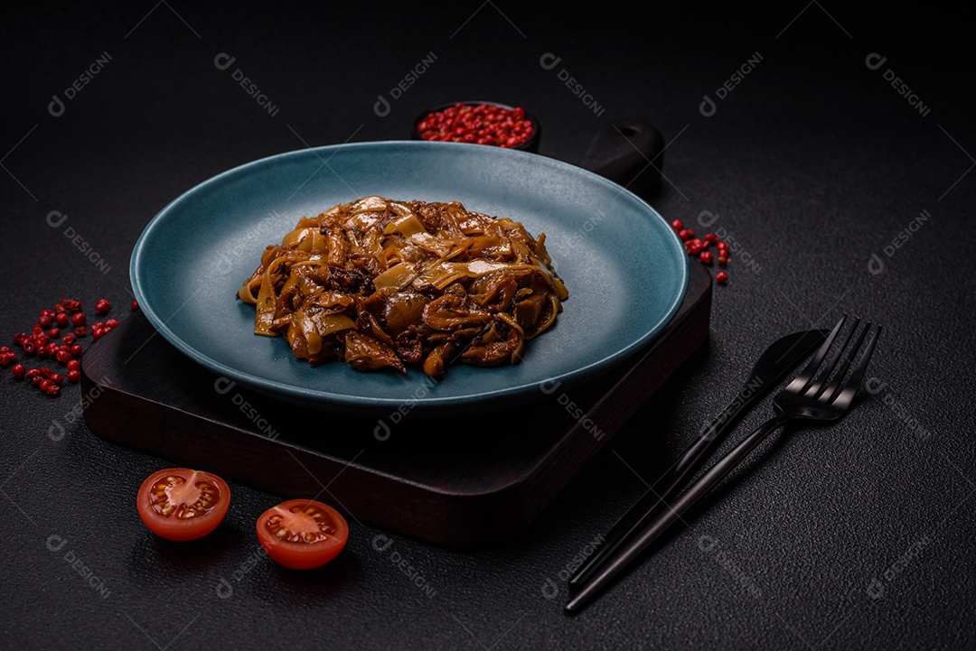 Delicioso prato de udon asiático com legumes, cogumelos, sal e especiarias numa placa cerâmica sobre um fundo escuro de concreto