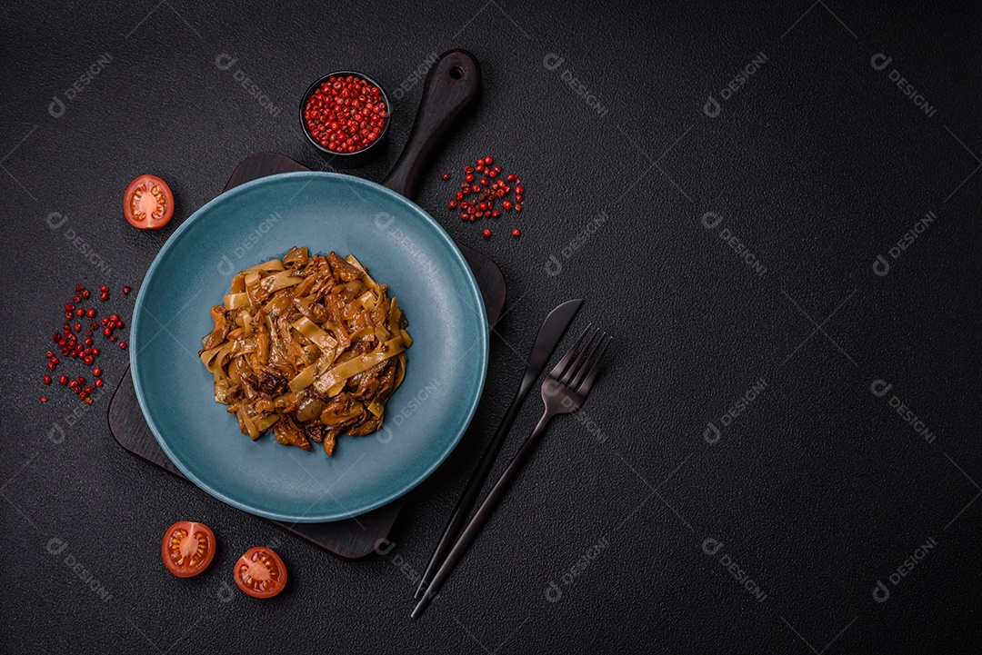 Delicioso prato de udon asiático com legumes, cogumelos, sal e especiarias numa placa cerâmica sobre um fundo escuro de concreto