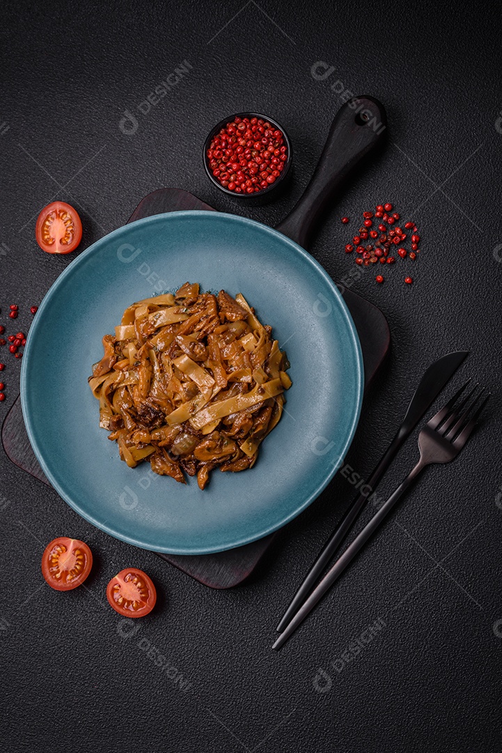 Delicioso prato de udon asiático com legumes, cogumelos, sal e especiarias numa placa cerâmica sobre um fundo escuro de concreto