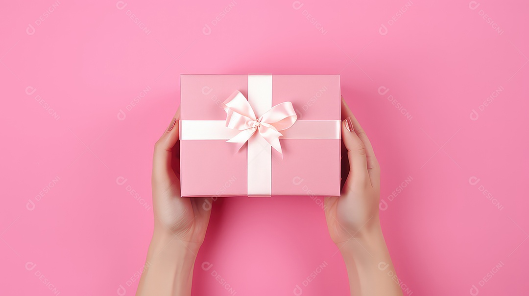 Mãos femininas segurando uma caixa de presente rosa em um fundo rosa