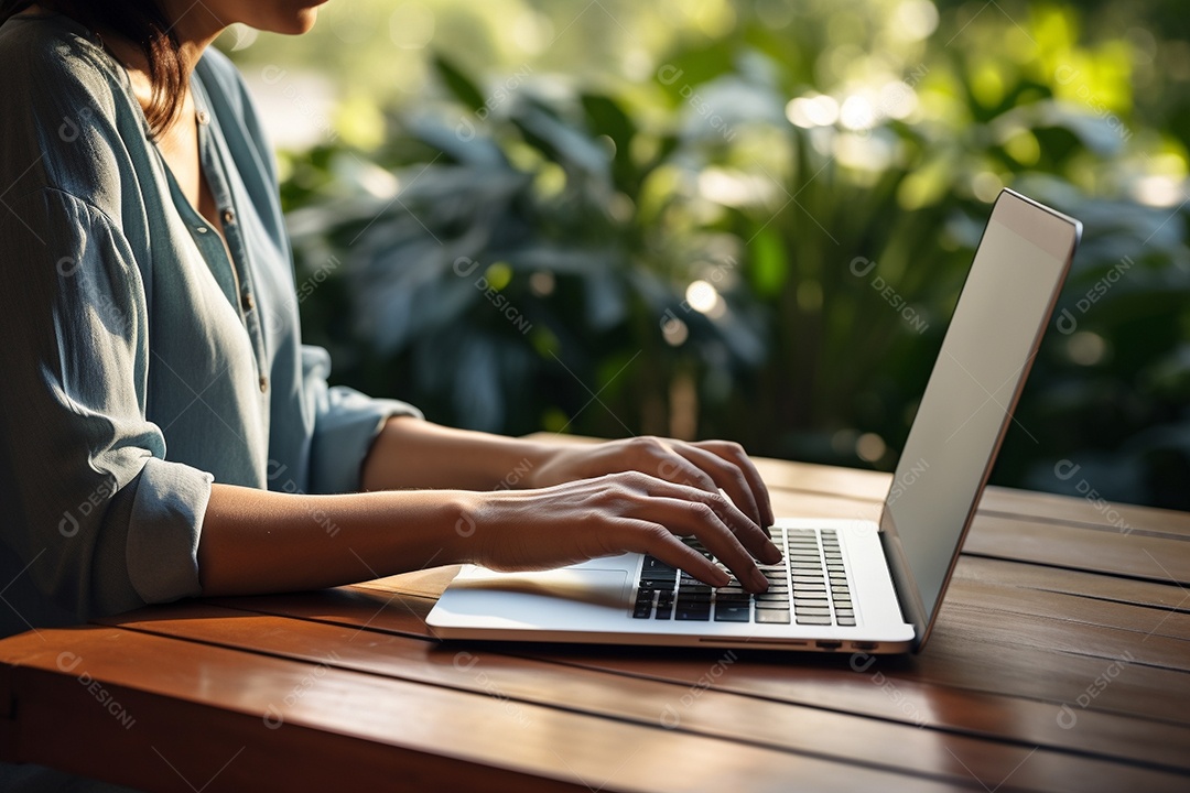 Mãos de uma pessoas digitando no notebook sobre uma mesa.