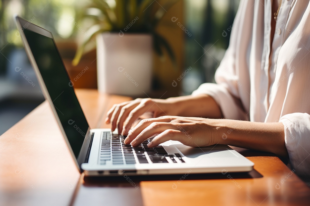 Mãos de uma pessoas digitando no notebook sobre uma mesa.