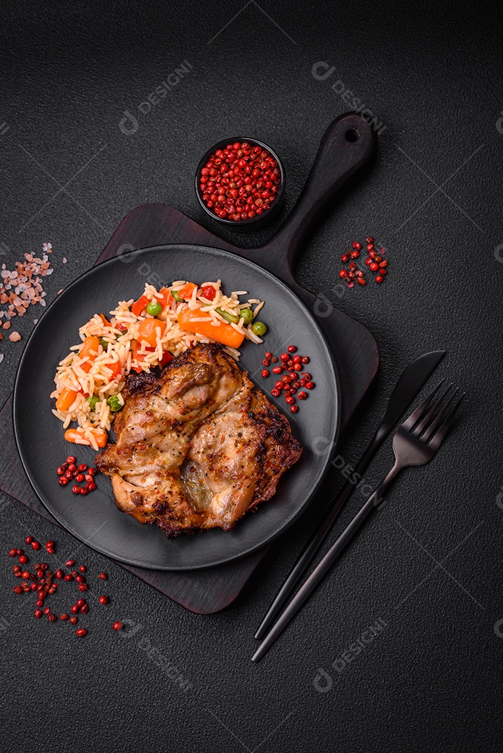 Delicioso arroz cozido com legumes, pimentas, ervilhas verdes, sal, especiarias e ervas sobre um fundo escuro de concreto