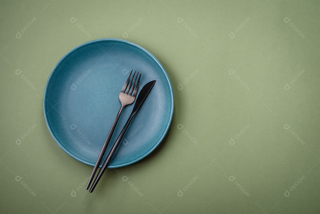 Placa cerâmica redonda vazia sobre um fundo liso. Utensílios de cozinha na cozinha de casa