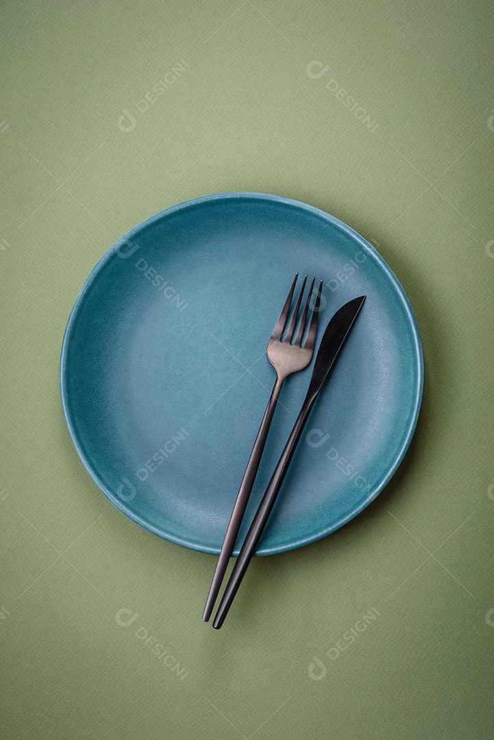 Placa cerâmica redonda vazia sobre um fundo liso. Utensílios de cozinha na cozinha de casa