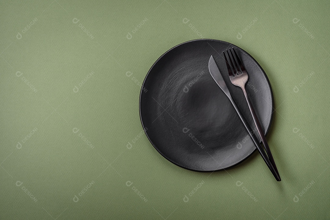 Placa cerâmica redonda vazia sobre um fundo liso. Utensílios de cozinha na cozinha de casa