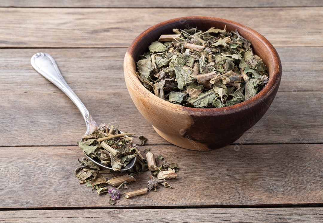 Folhas de erva-cidreira ou Melissa secas em uma tigela sobre fundo de madeira