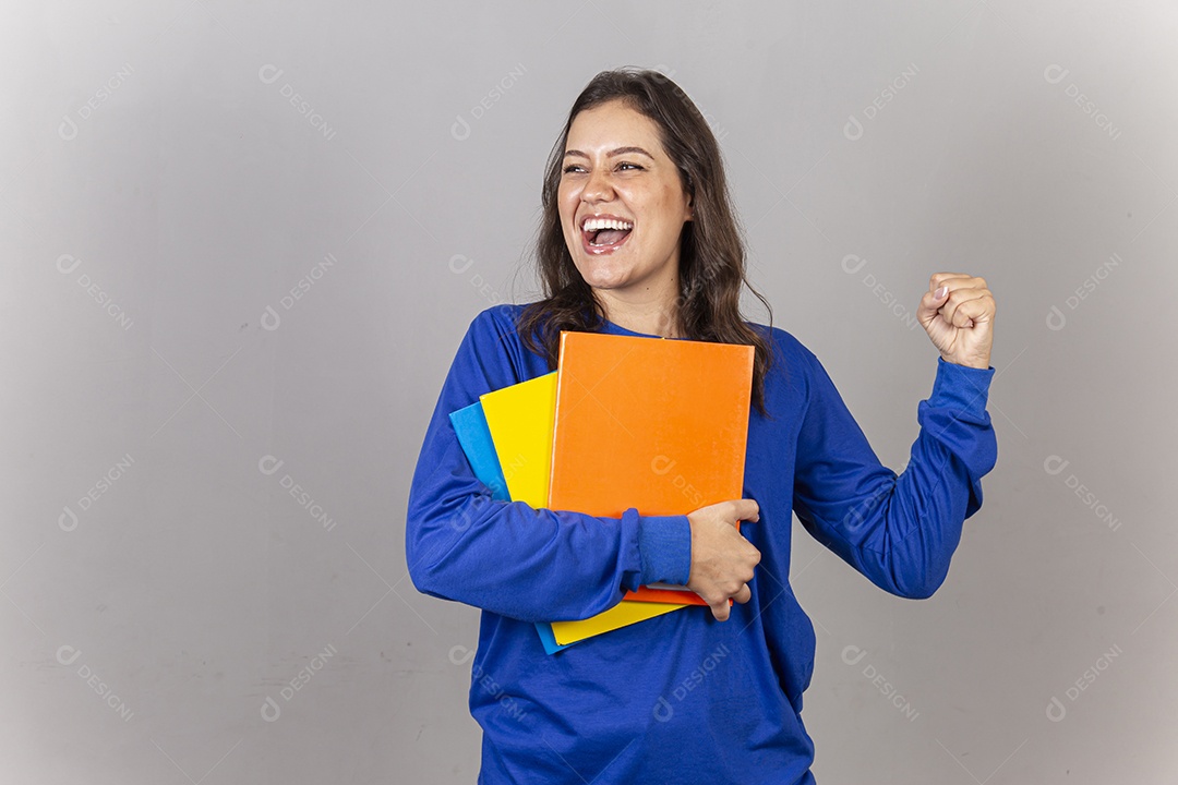 Jovem mulher vestida com moletom azul segurando celular e livros.