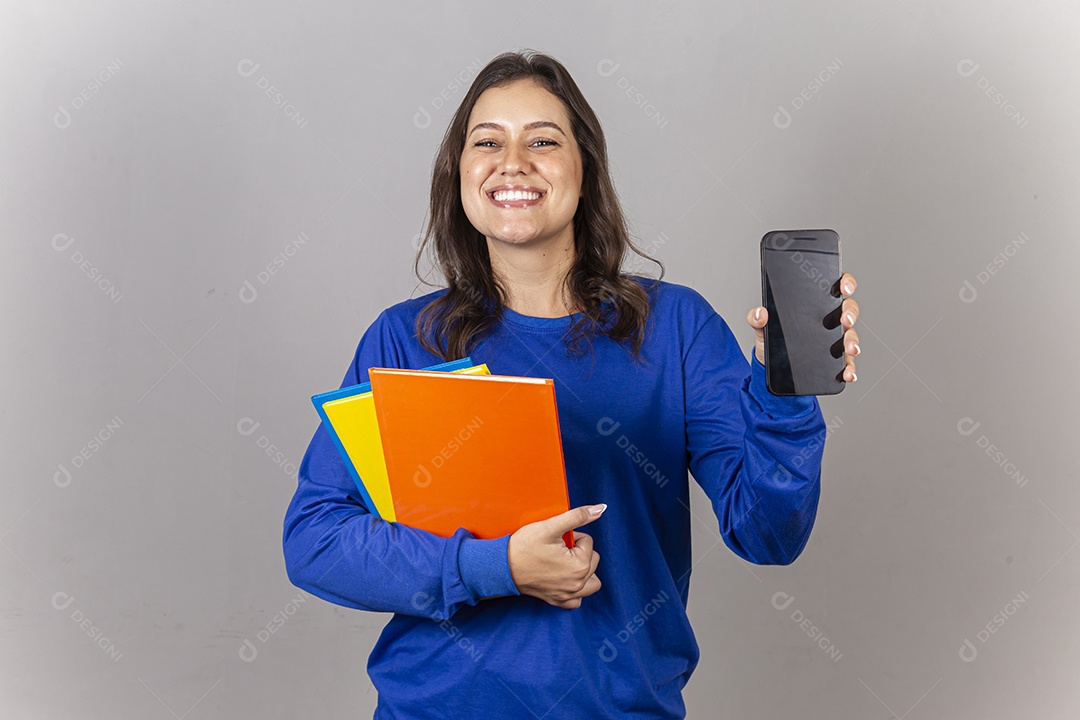 Jovem mulher vestida com moletom azul segurando celular e livros.