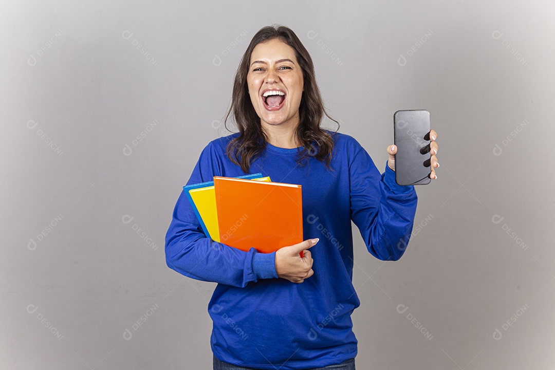 Jovem mulher vestida com moletom azul segurando celular e livros.