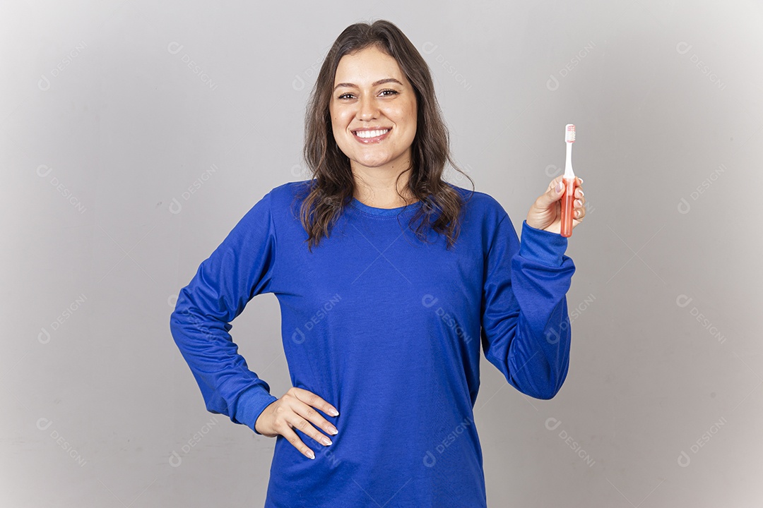 Mulher vestida com moletom azul segurando escova dental.