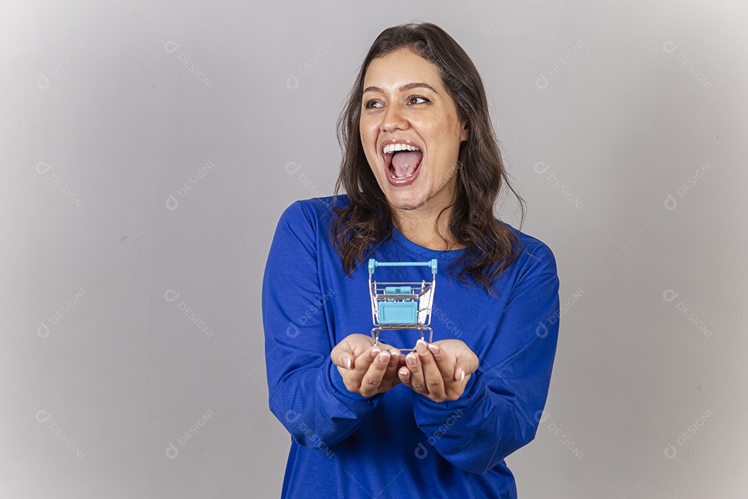 Linda mulher sorridente com mini carrinho de supermercado na mão.
