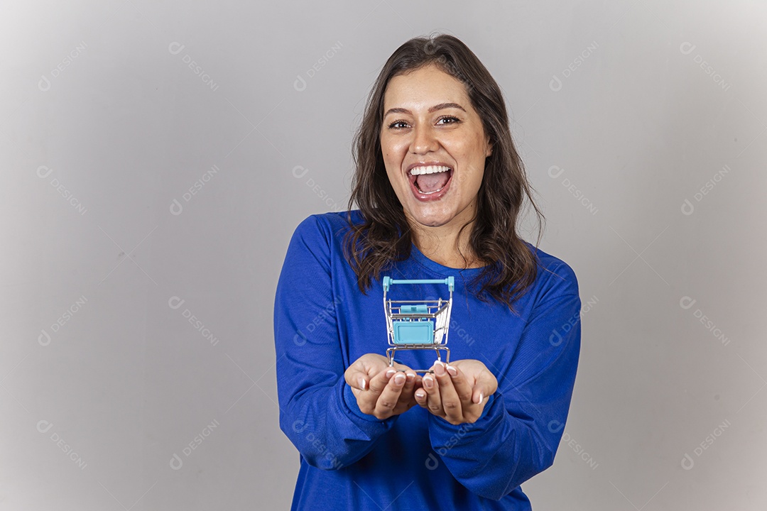 Linda  mulher sorridente com um mini carrinho e supermercado na mão.