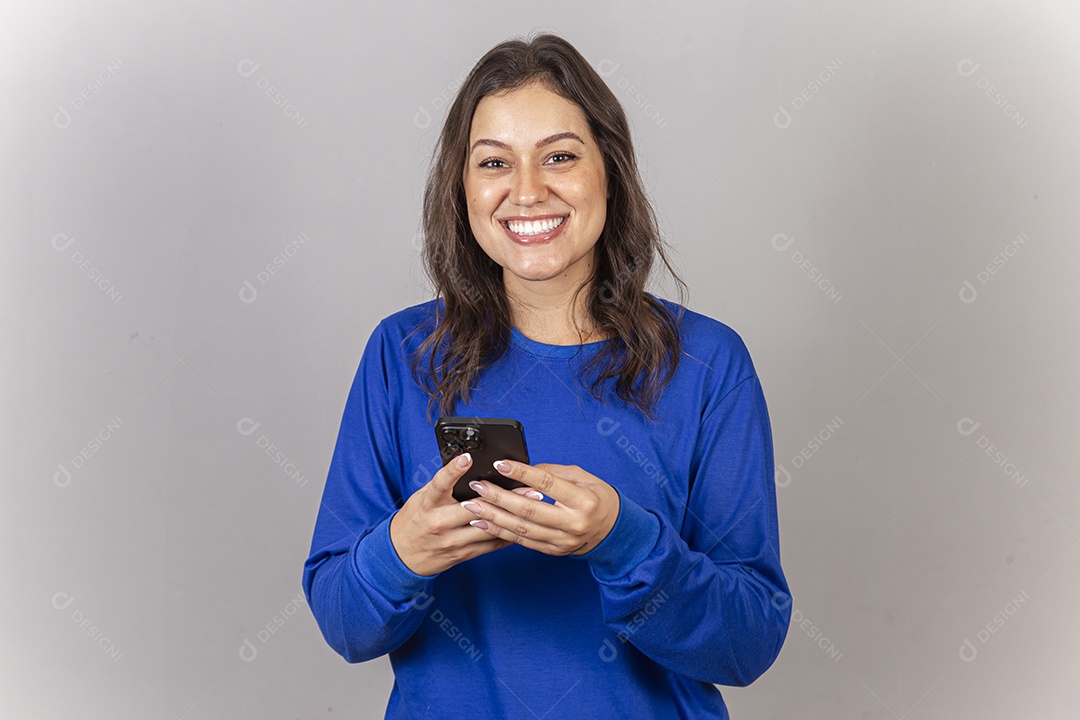 Linda mulher sorridente com celular na mão vestida com moletom azul.