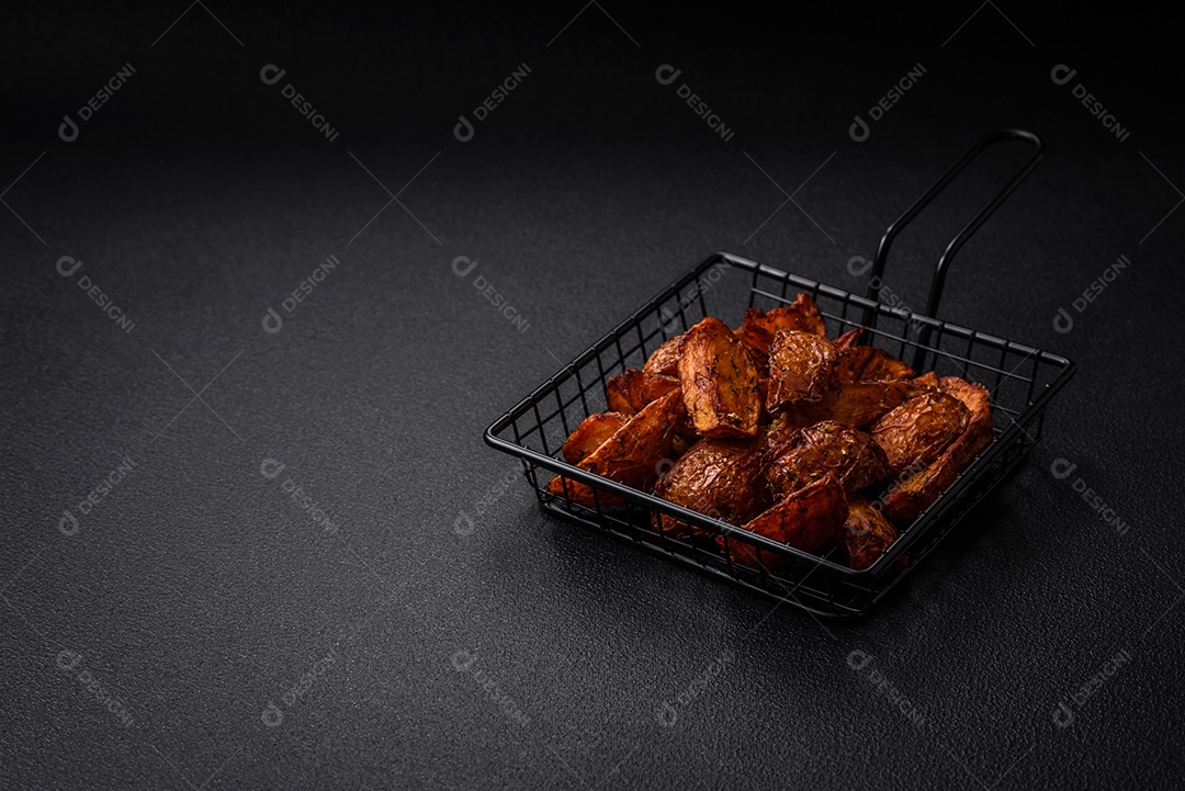 Deliciosas fatias de batata crocante com alho, sal, especiarias e ervas sobre um fundo escuro de concreto