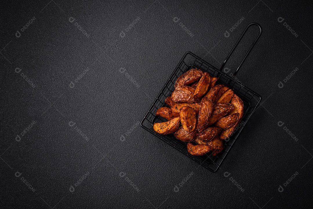 Deliciosas fatias de batata crocante com alho, sal, especiarias e ervas sobre um fundo escuro de concreto