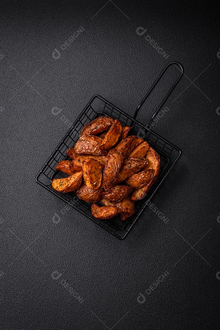 Deliciosas fatias de batata crocante com alho, sal, especiarias e ervas sobre um fundo escuro de concreto