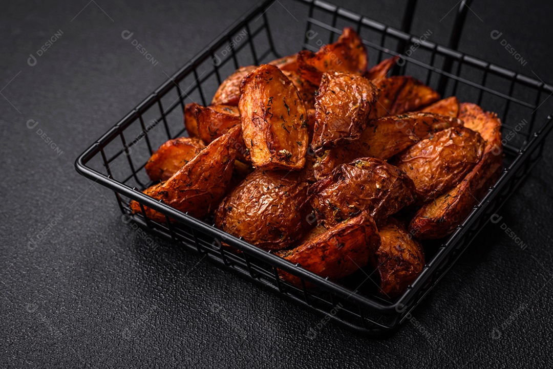 Deliciosas fatias de batata crocante com alho, sal, especiarias e ervas sobre um fundo escuro de concreto