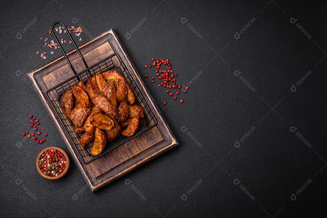 Deliciosas fatias de batata crocante com alho, sal, especiarias e ervas sobre um fundo escuro de concreto