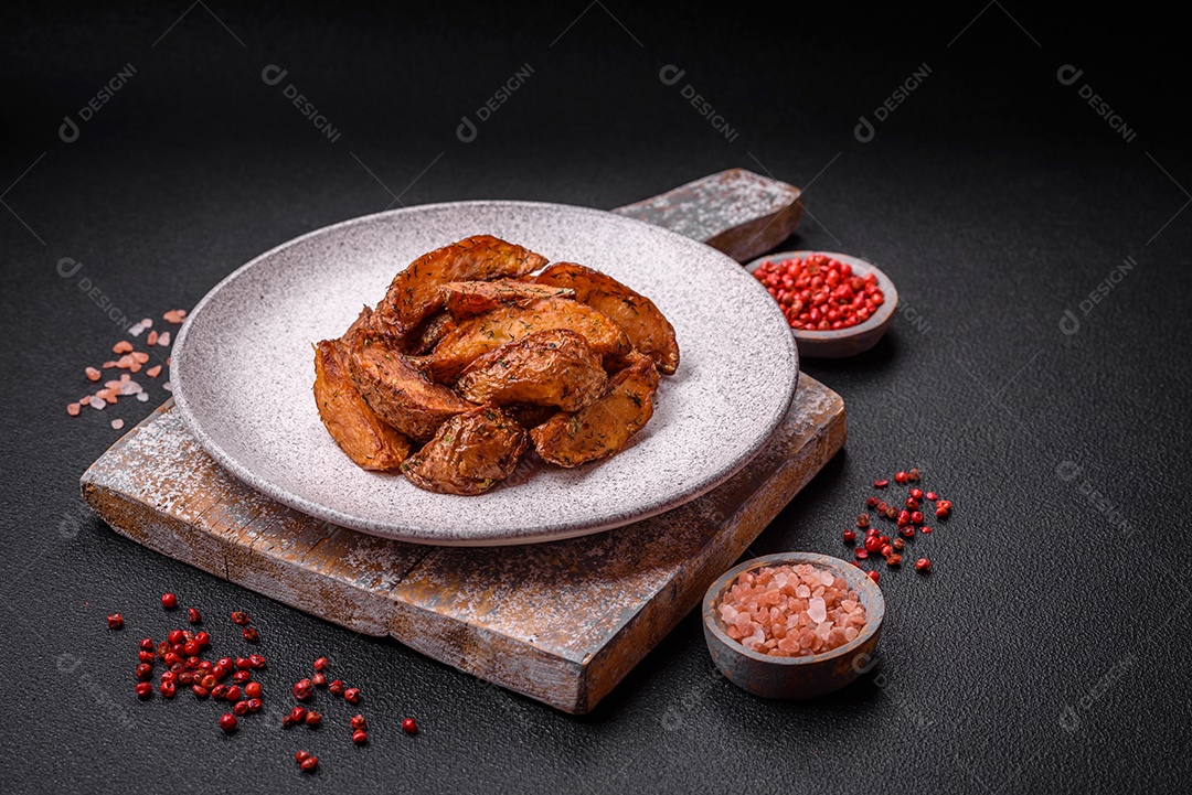 Deliciosas fatias de batata crocante com alho, sal, especiarias e ervas sobre um fundo escuro de concreto