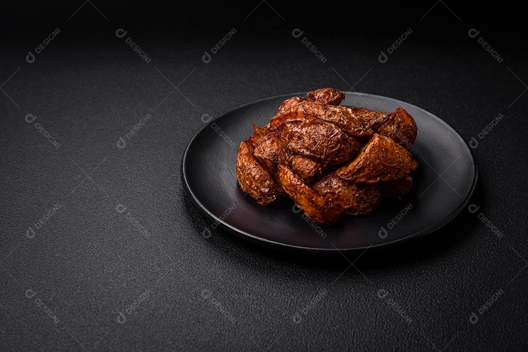 Deliciosas fatias de batata crocante com alho, sal, especiarias e ervas sobre um fundo escuro de concreto