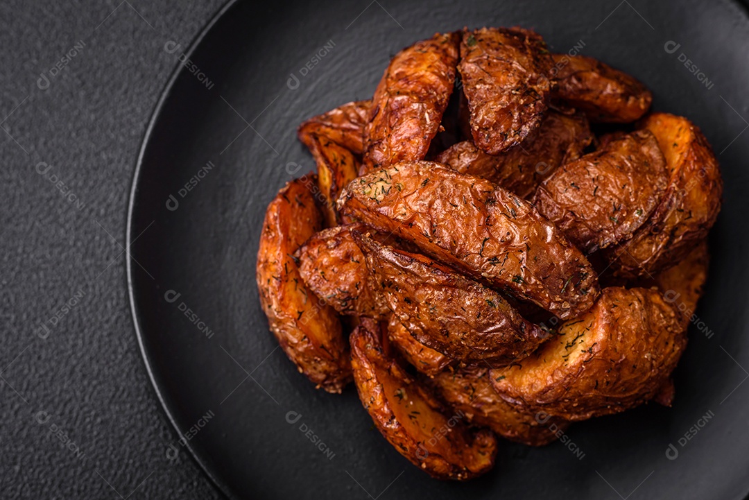 Deliciosas fatias de batata crocante com alho, sal, especiarias e ervas sobre um fundo escuro de concreto