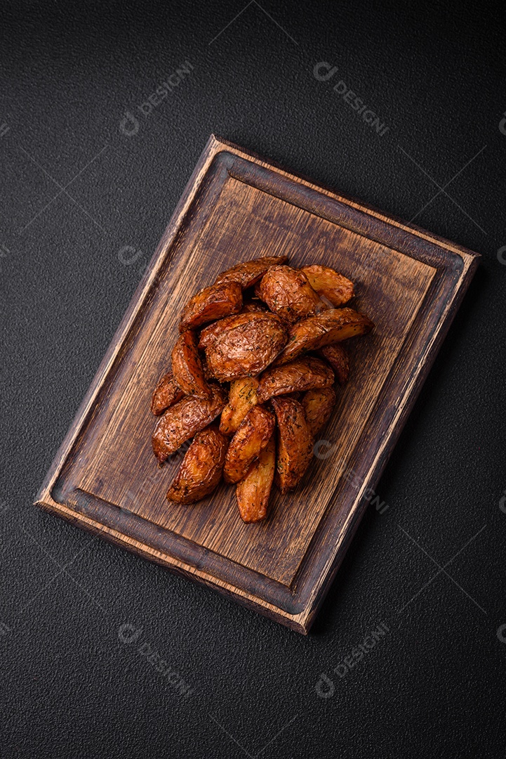 Deliciosas fatias de batata crocante com alho, sal, especiarias e ervas sobre um fundo escuro de concreto