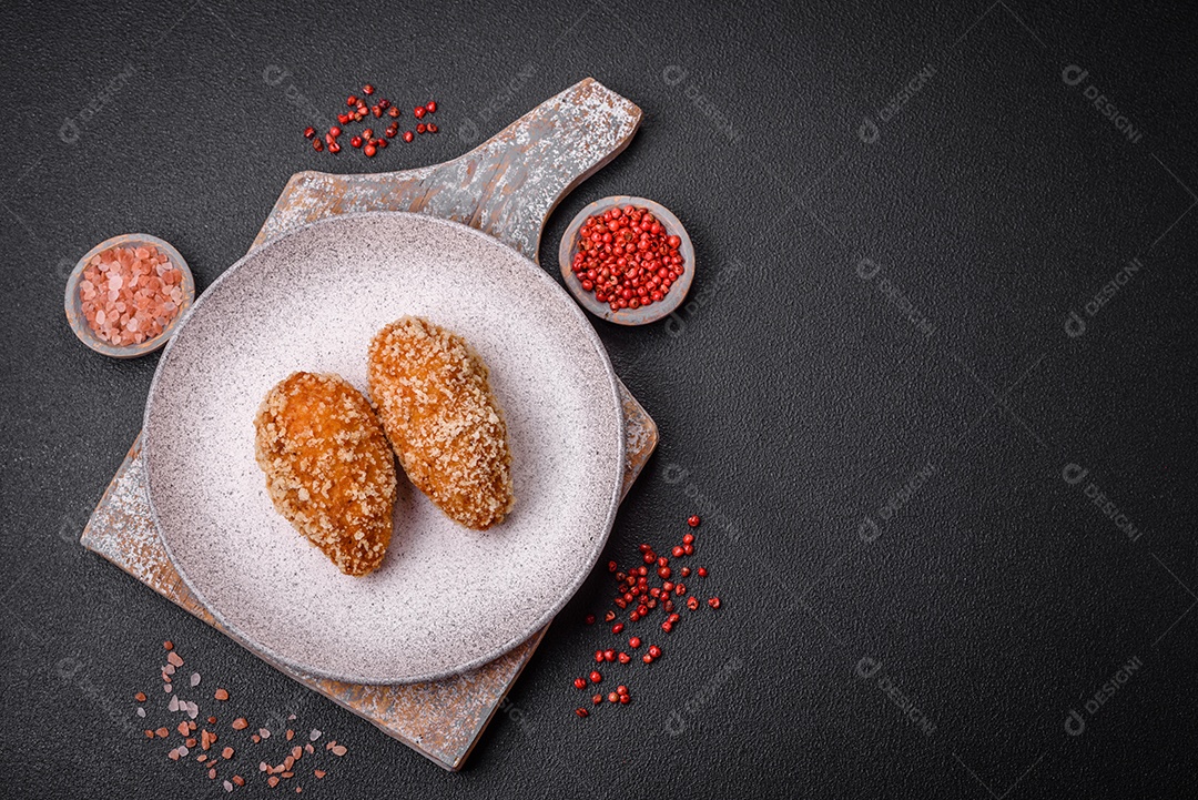 Delicioso frango frito suculento ou panquecas de porco com sal, especiarias e ervas sobre um fundo escuro de concreto