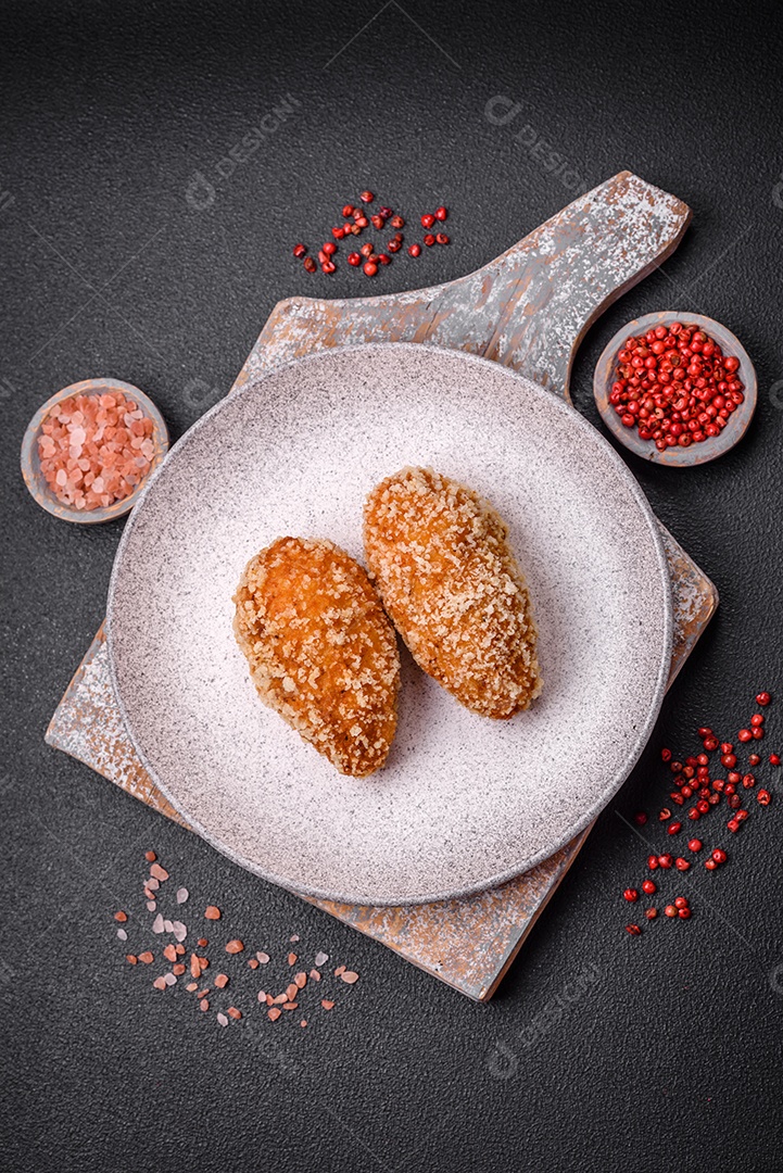 Delicioso frango frito suculento ou panquecas de porco com sal, especiarias e ervas sobre um fundo escuro de concreto