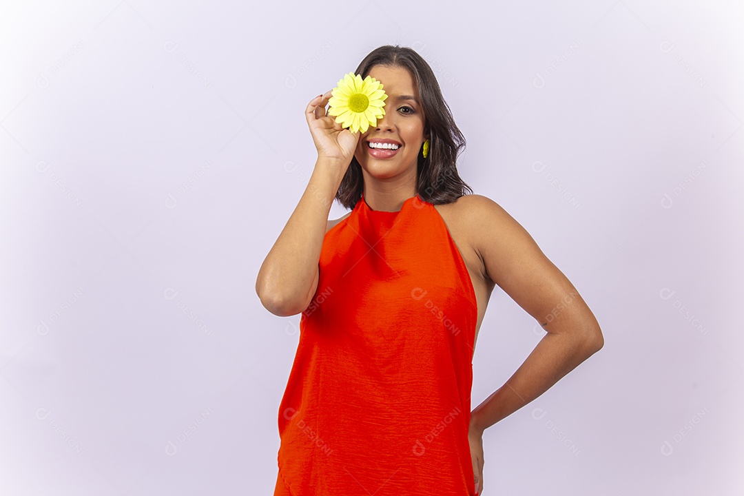 Mulher linda usando vestido laranja segurando uma flor sobre um fundo isolado branco.