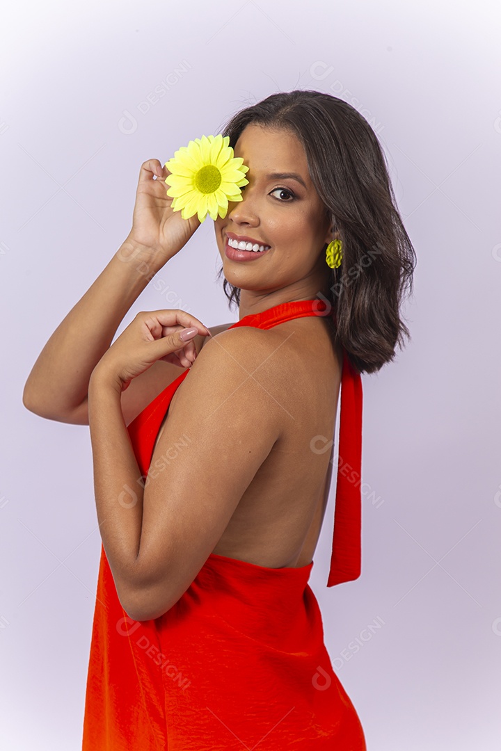 Mulher linda usando vestido laranja segurando uma flor sobre um fundo isolado branco.