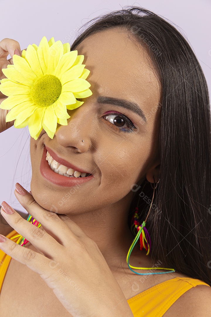 Linda mulher sorridente segurando uma flor amarela sobre o olho.