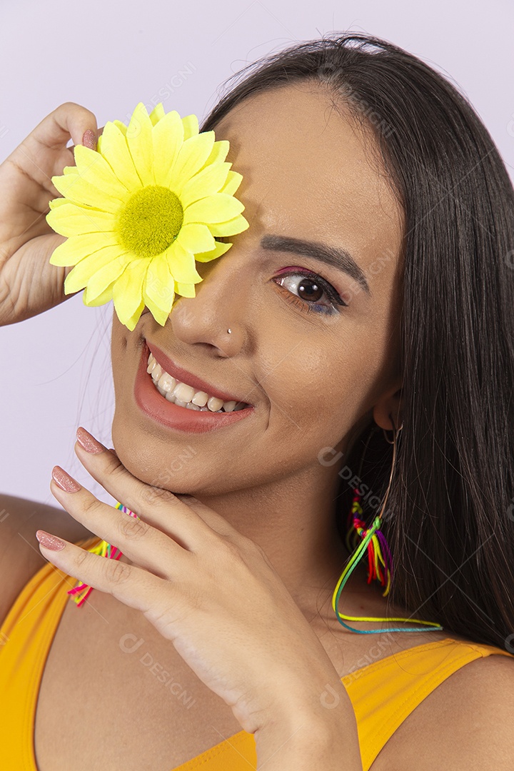 Linda mulher sorridente segurando uma flor amarela sobre o olho.