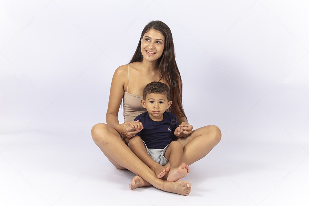 Mãe sentada no chão com filho no colo sobre um fundo branco.