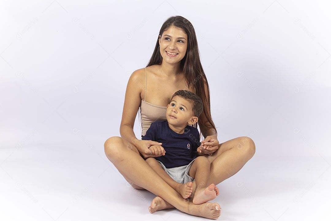 Mãe sentada no chão com filho no colo sobre um fundo branco.